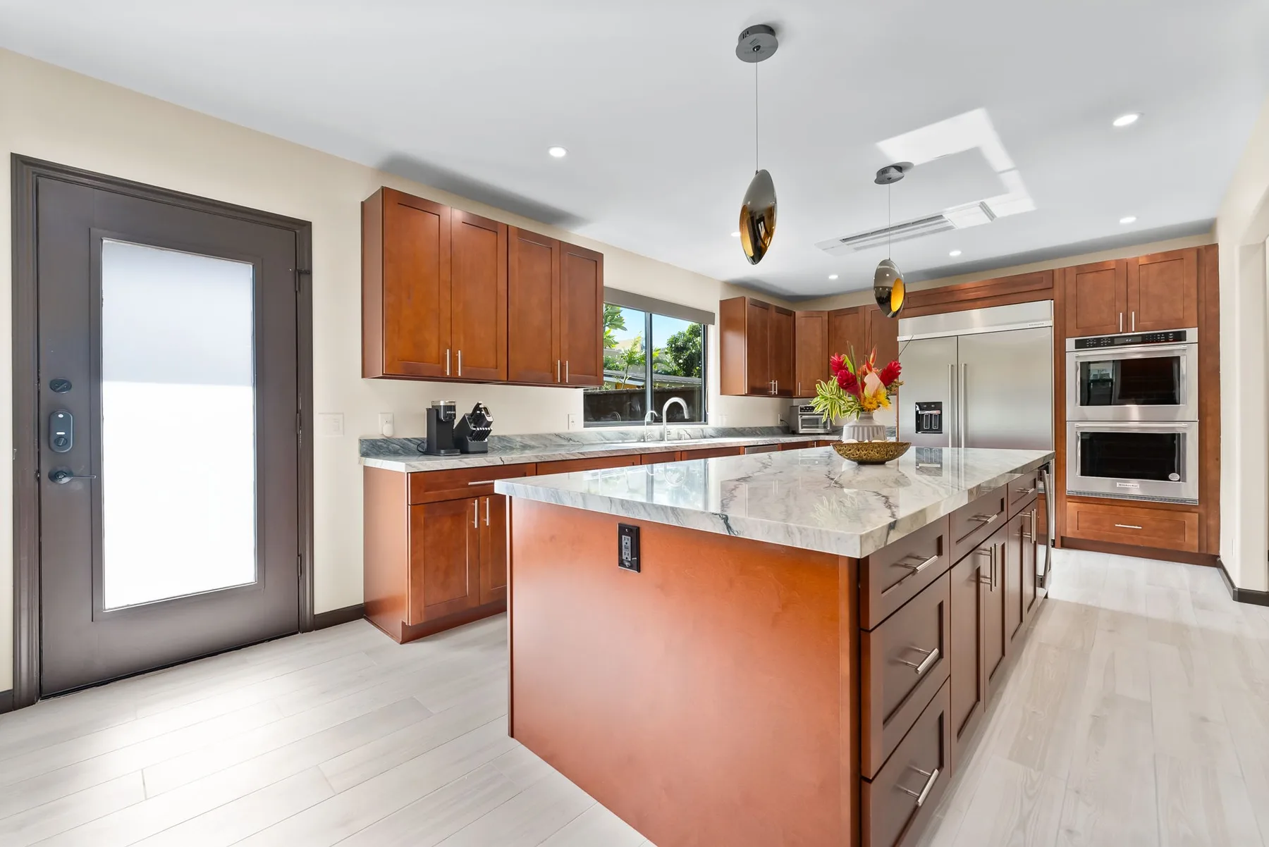 A bright kitchen with wood cabinets, stainless steel appliances, and a large central island.