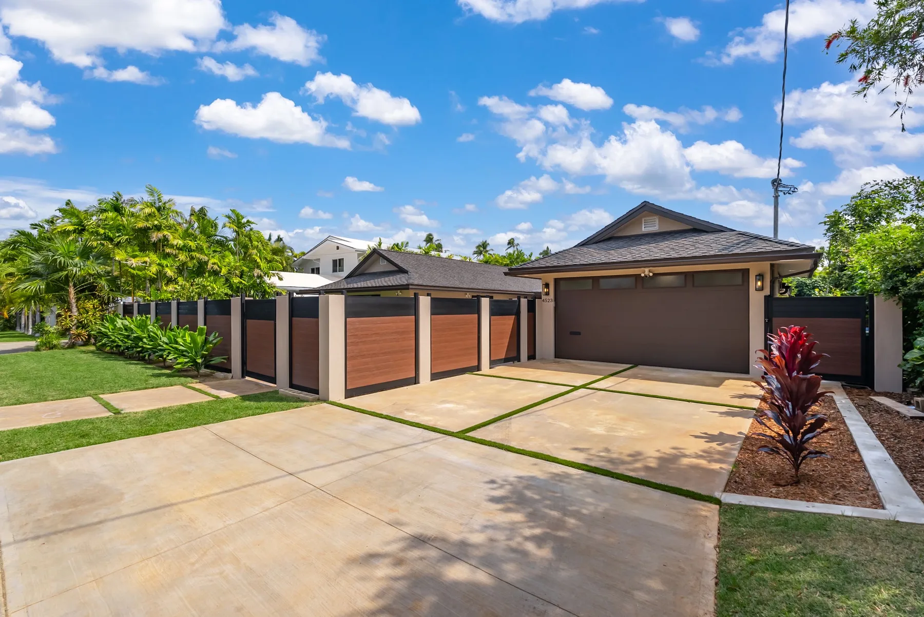 A residential driveway and garage sit behind a modern gated fence.