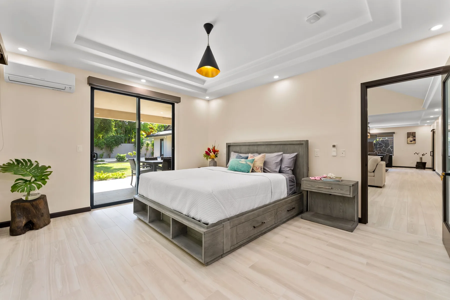 A bedroom with a large bed beside sliding glass doors opening to a garden.
