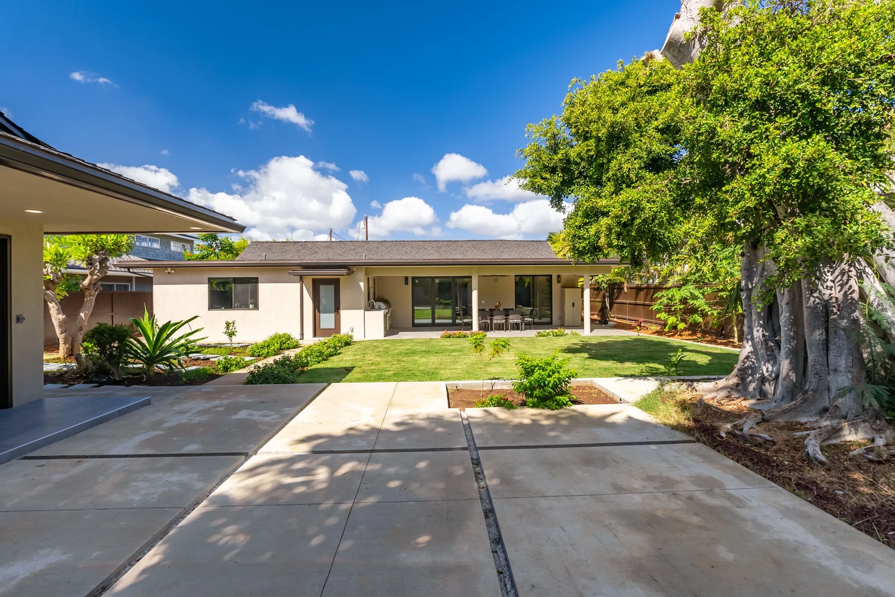 A single-story house faces a paved driveway and a landscaped yard.