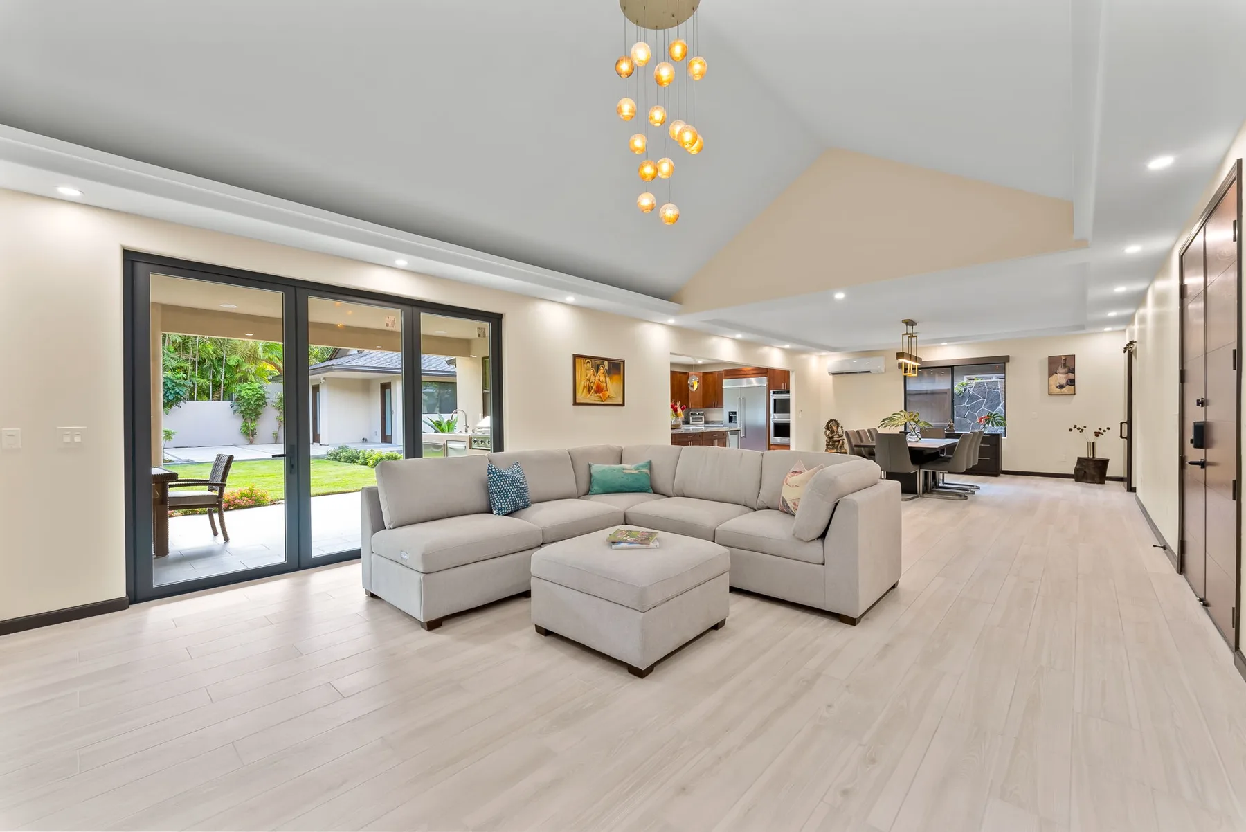 A bright open-plan living area with sectional seating and sliding glass doors.