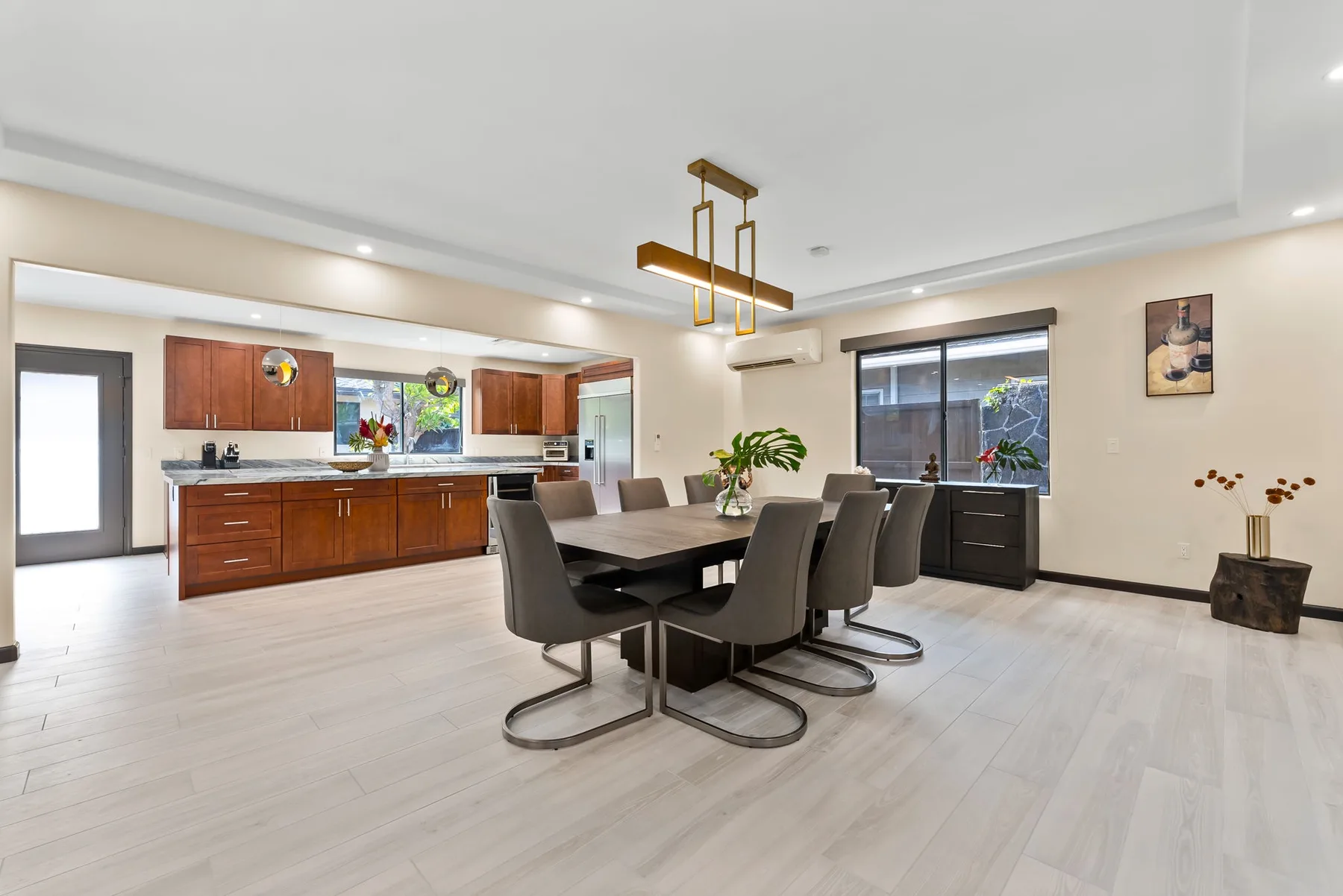 An open dining area with a dark table and seating beside a kitchen.