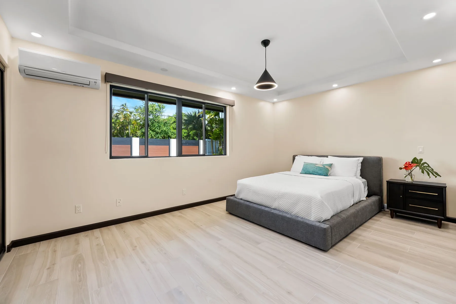 A bedroom with a bed, a window, and a bedside table.