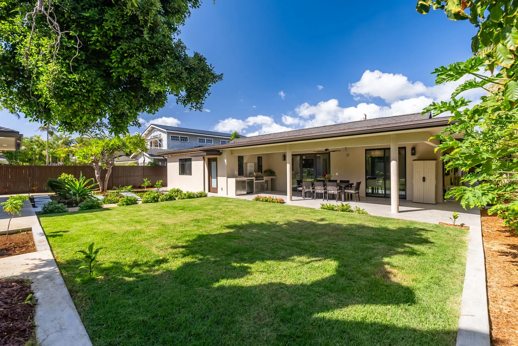 A landscaped backyard lawn with a covered patio beside the house.