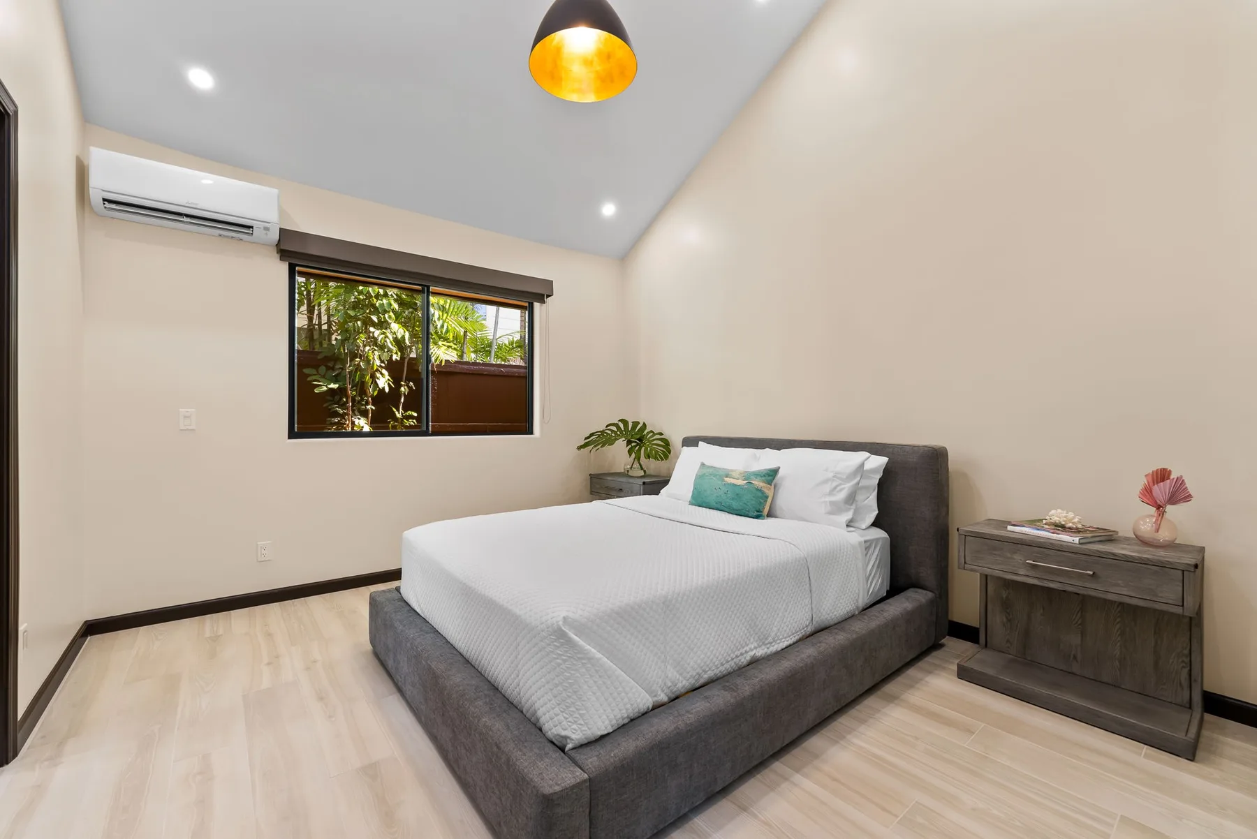 A bedroom with a neatly made bed, bedside table, and window.