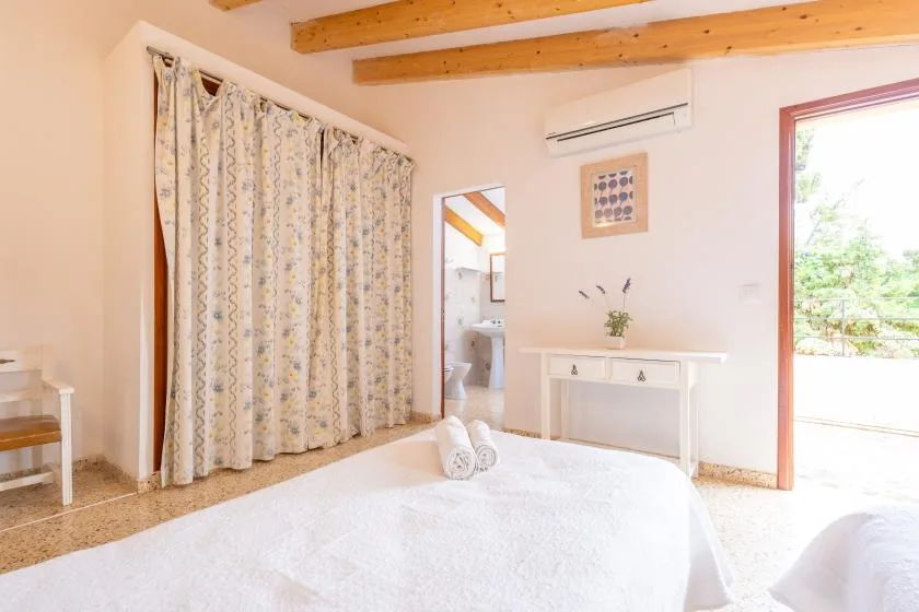 A bright bedroom with a bed, patterned curtains, and an open doorway.