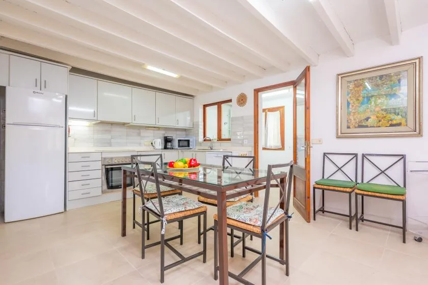 A bright kitchen and dining area with a table, chairs, and white cabinets.