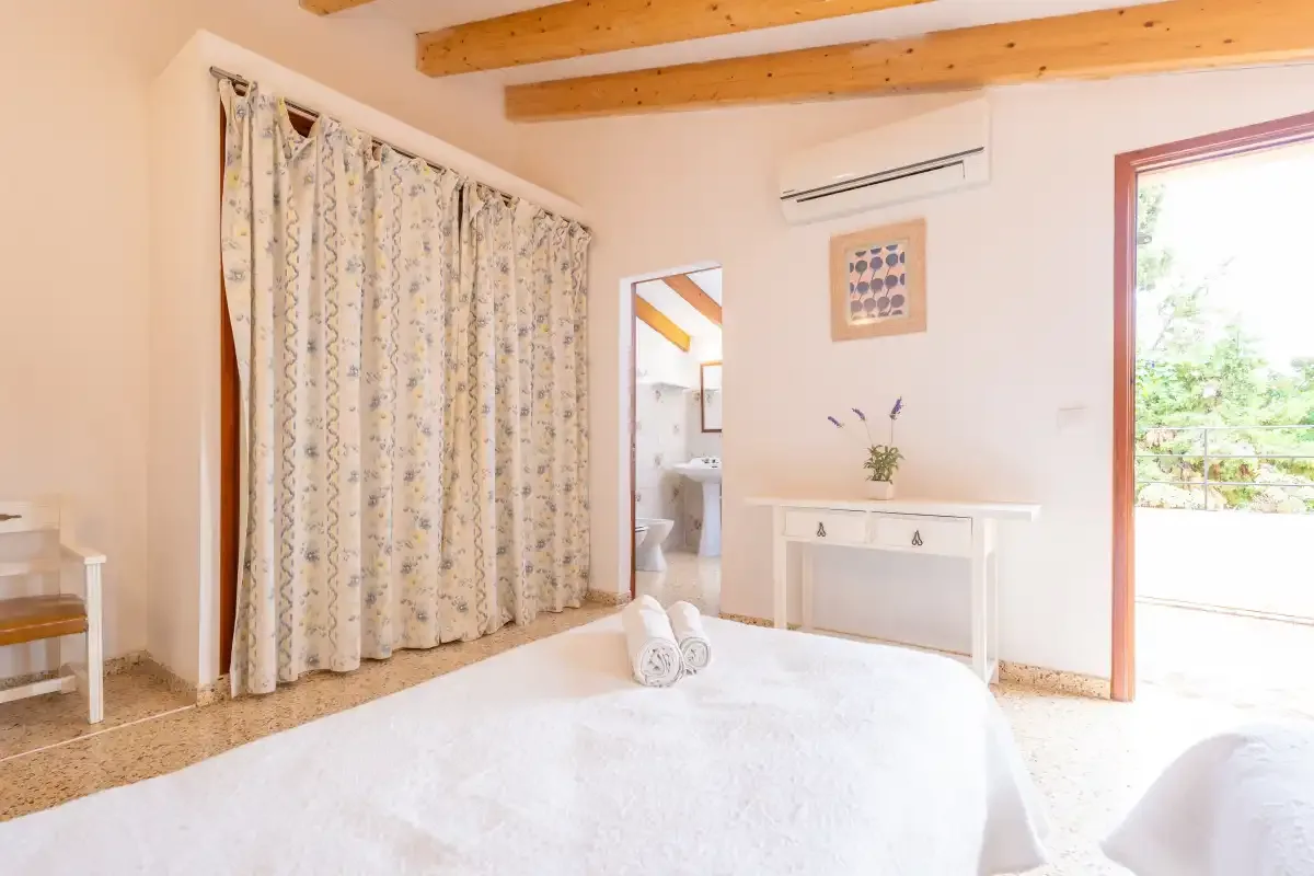 A bedroom with a large bed, patterned curtains, and an open doorway.