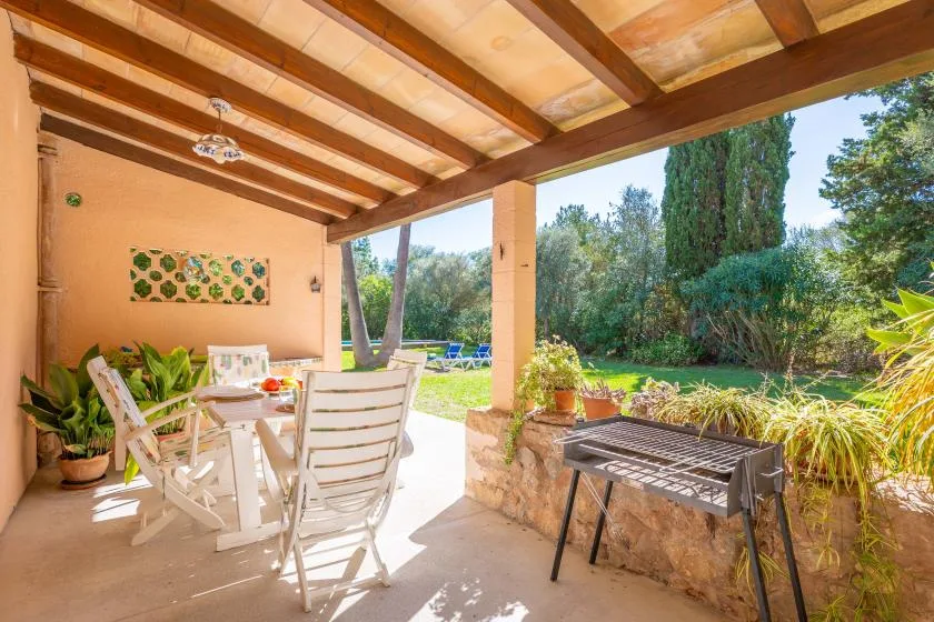 A covered outdoor dining area opens onto a green garden.