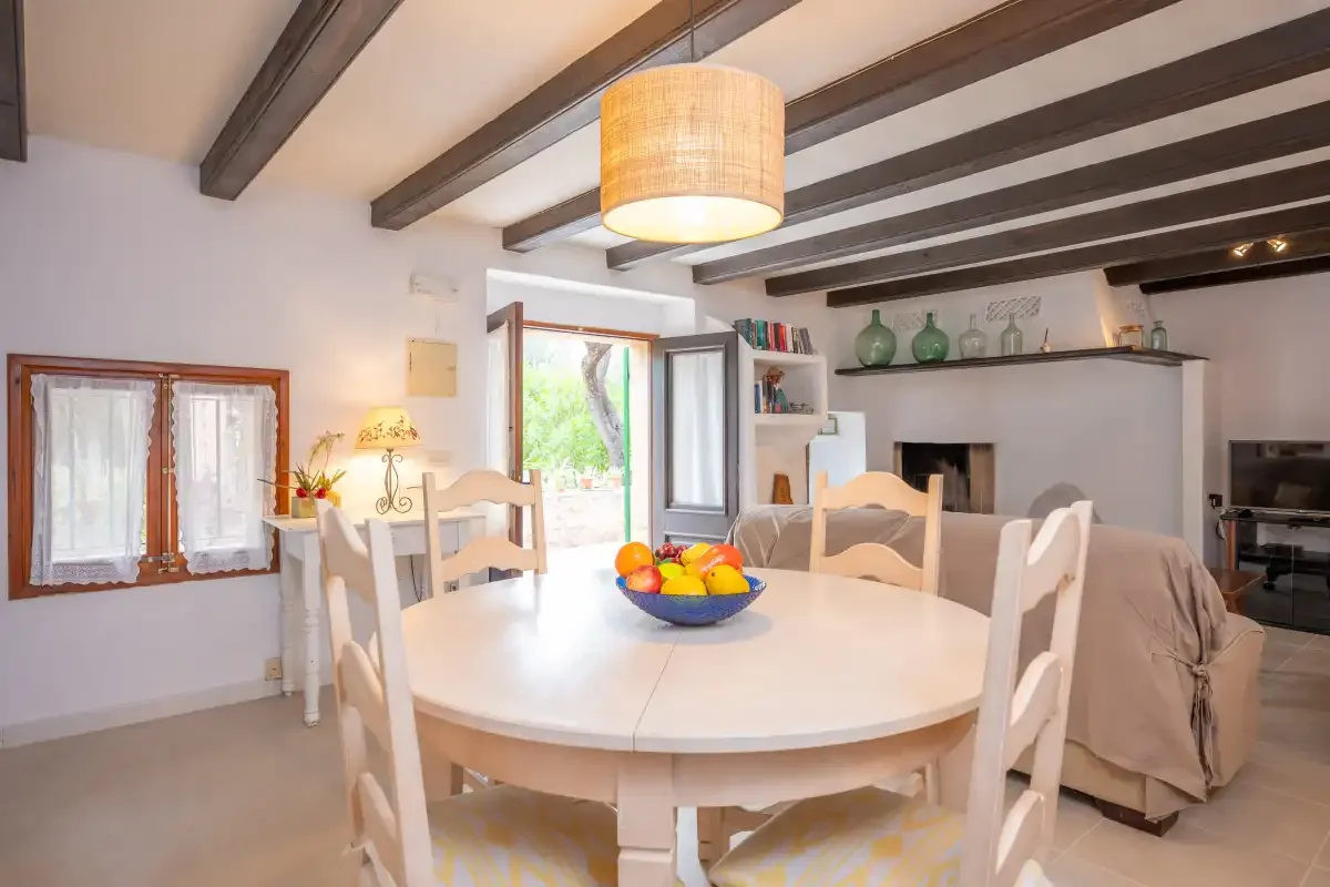 A dining area with a round table and chairs beside a living area.