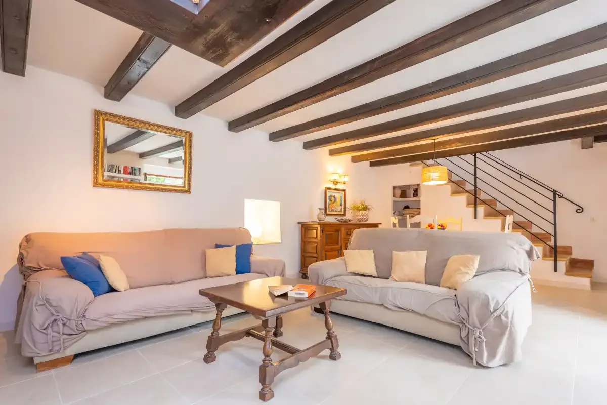 A living room with seating, a coffee table, and exposed ceiling beams.