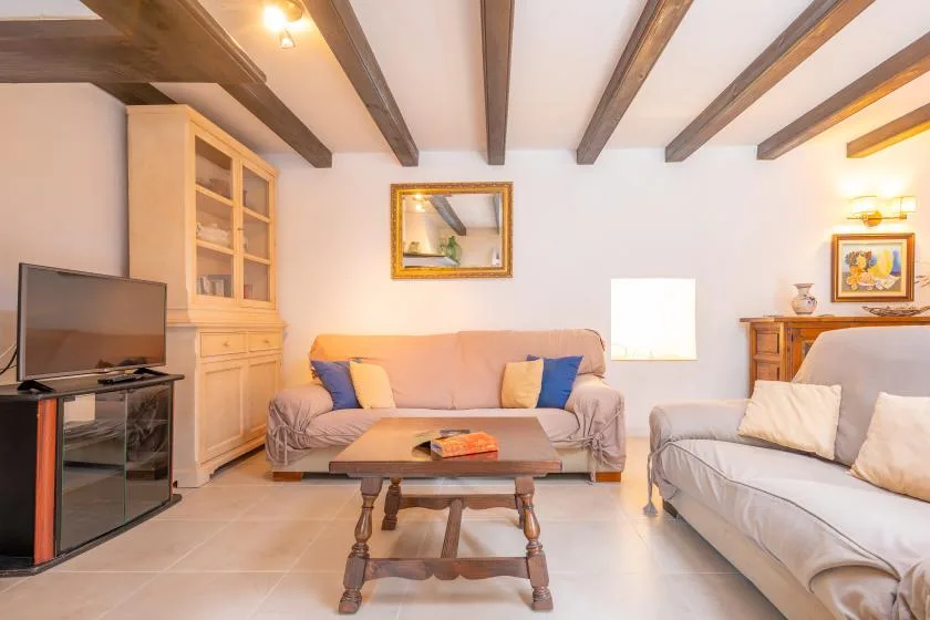 A living room with sofas, a coffee table, and exposed ceiling beams.