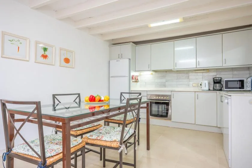 A bright kitchen and dining area with a glass-topped table and white cabinets.
