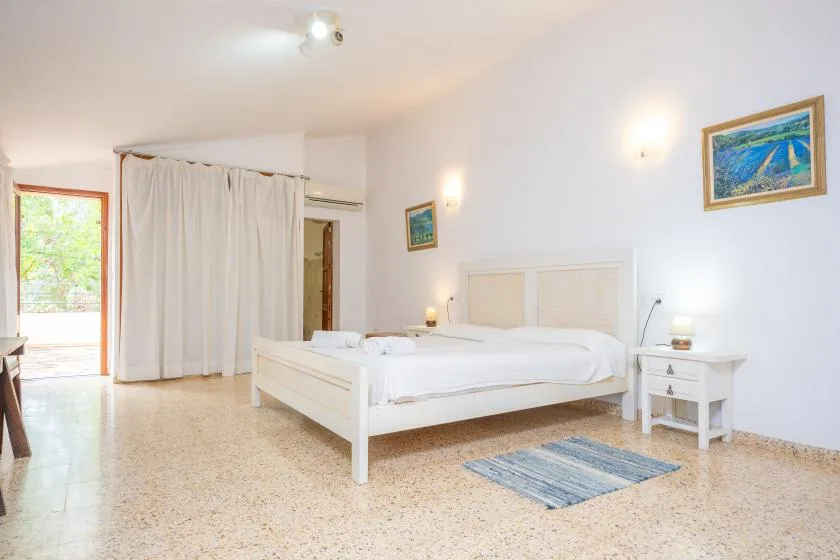 A bright bedroom with a white bed, bedside tables, and framed artwork.