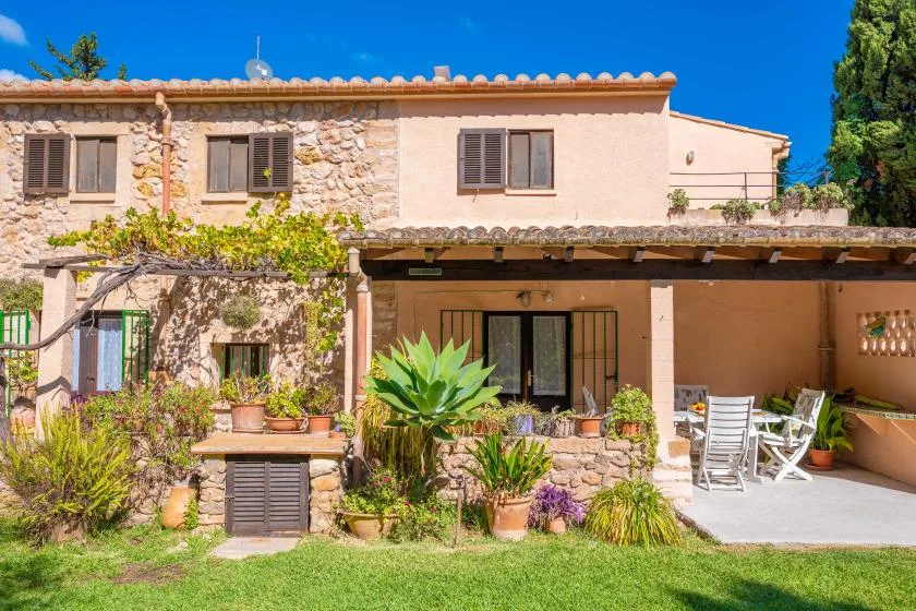 A stone-and-plaster house with a covered patio opening onto a garden.
