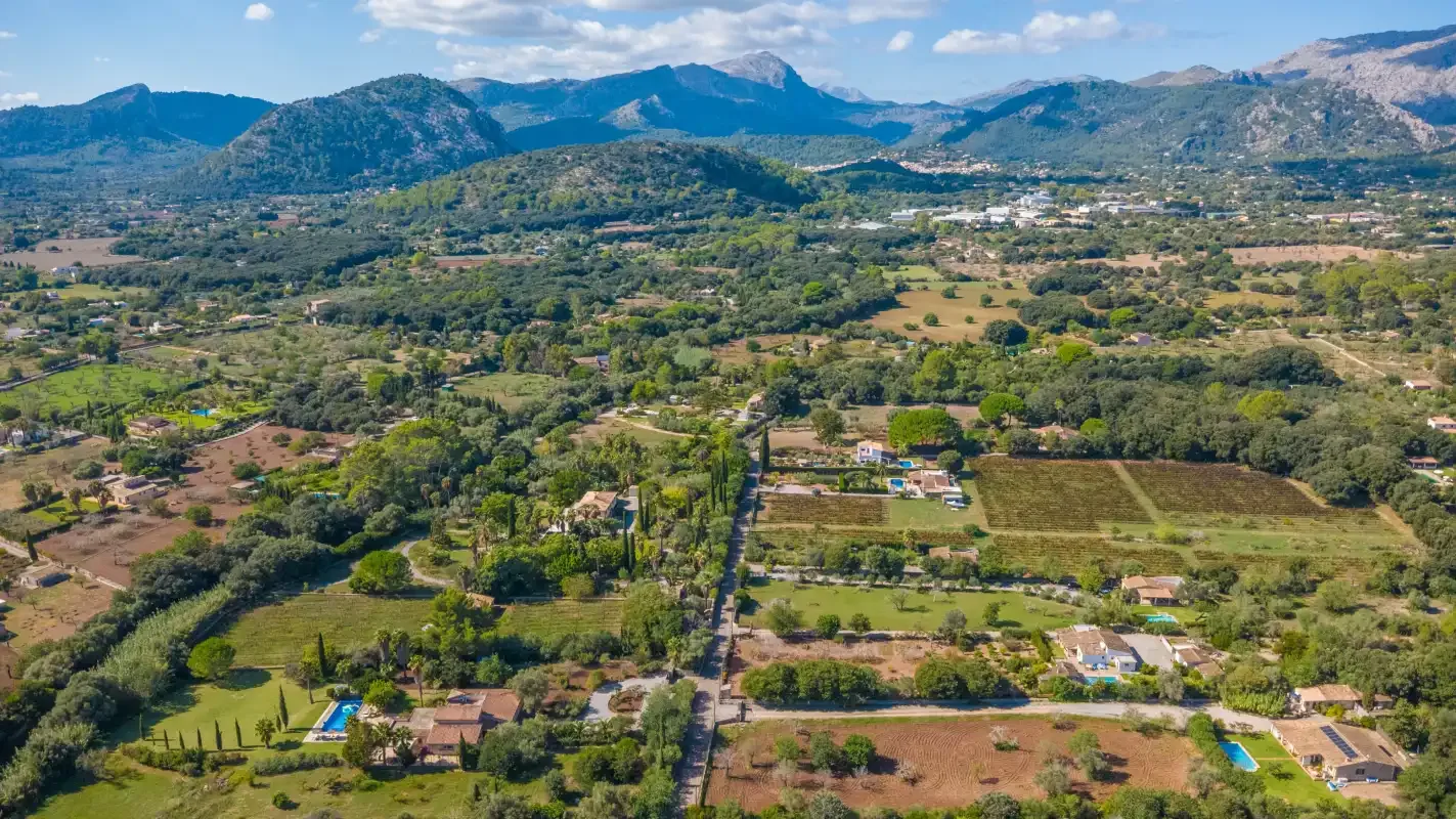 Aerial view of a rural valley with fields, homes, and mountains.