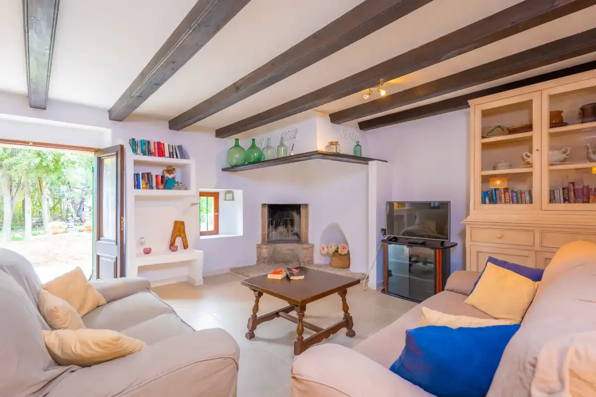 A living room with seating, a coffee table, and an open doorway to greenery.