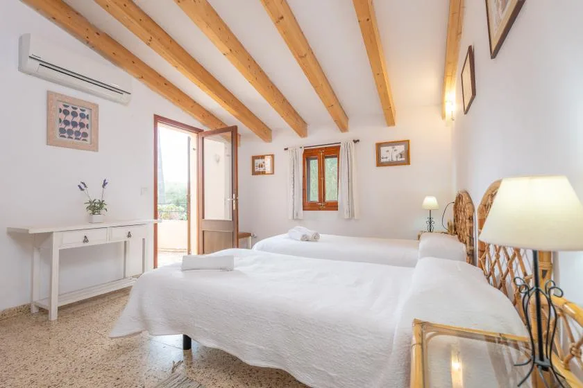 A bright bedroom with white bedding and exposed wooden ceiling beams.