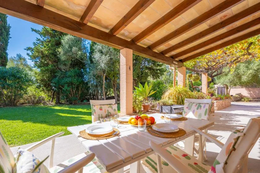 A covered outdoor dining area overlooks a green garden.