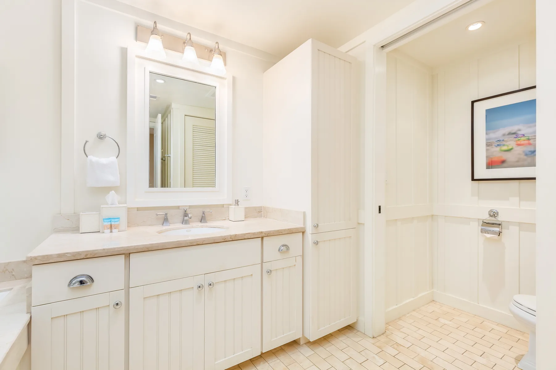 Un baño luminoso con un tocador largo, un espejo y suelo de baldosas.