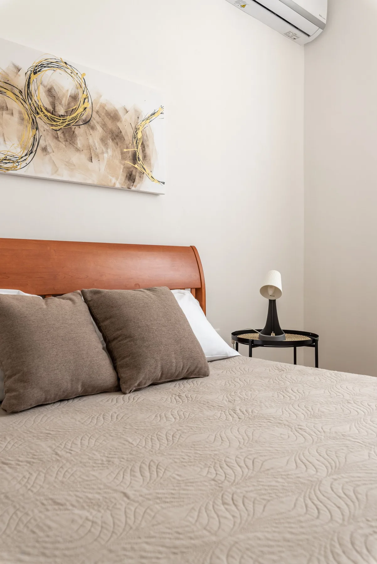 Un dormitorio con una cama, arte abstracto en la pared y una mesita de noche.