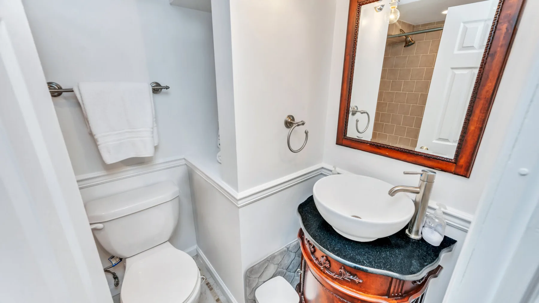 Un tocador de baño con lavabo y espejo está junto a un inodoro.