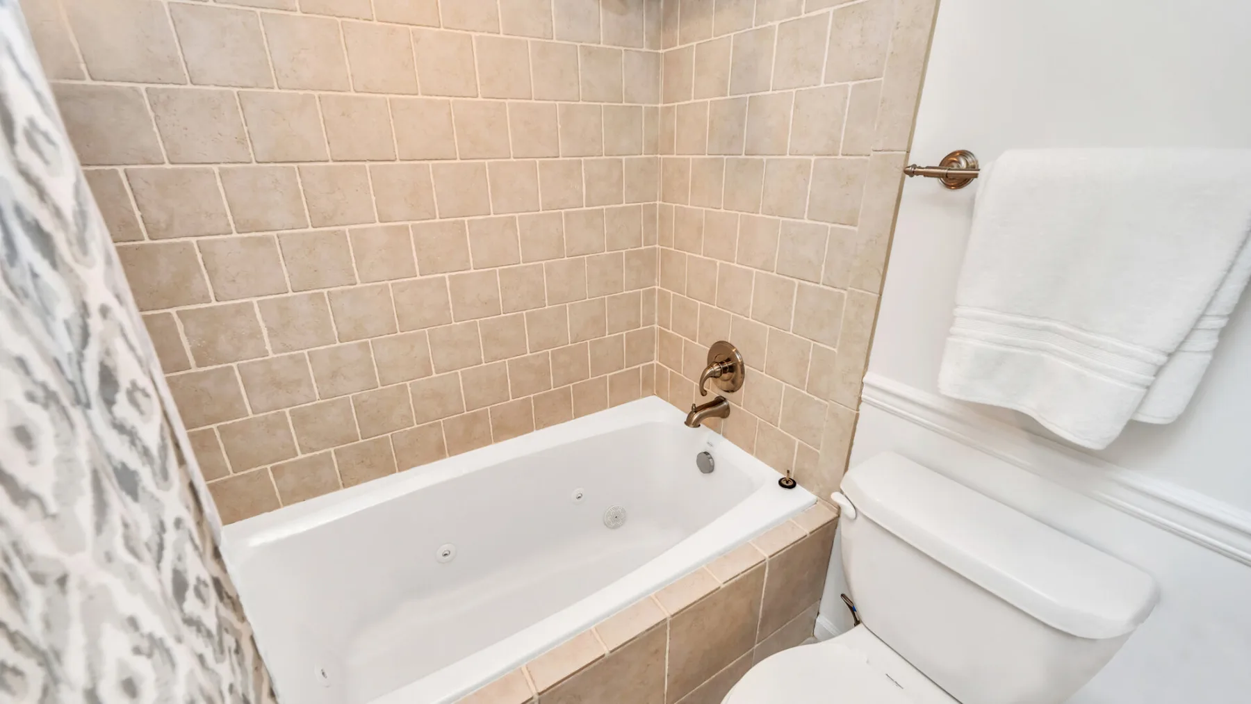 Un baño con bañera, paredes de azulejos e inodoro.