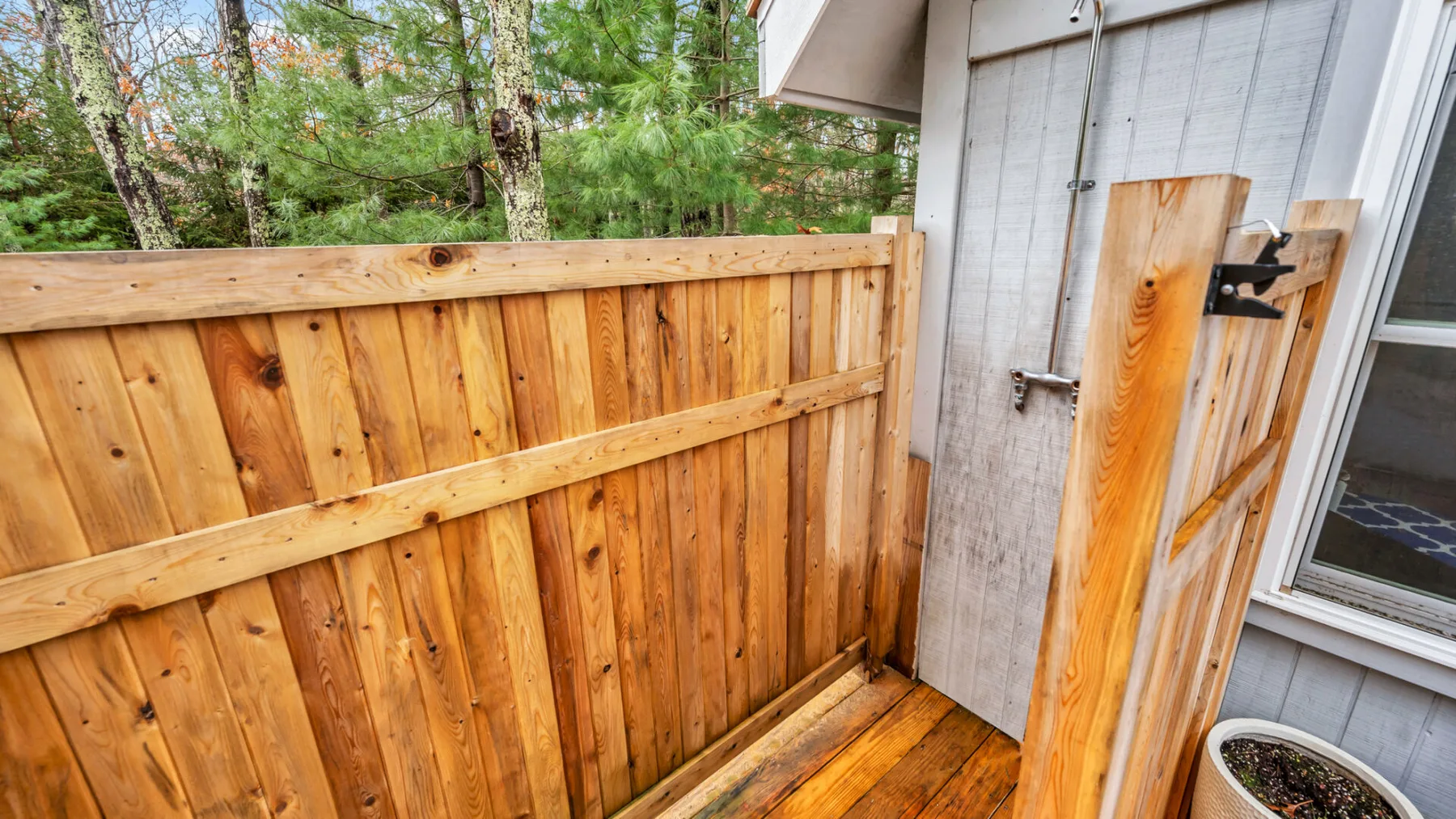 Una pequeña terraza exterior con una cerca de madera junto a una pared clara.