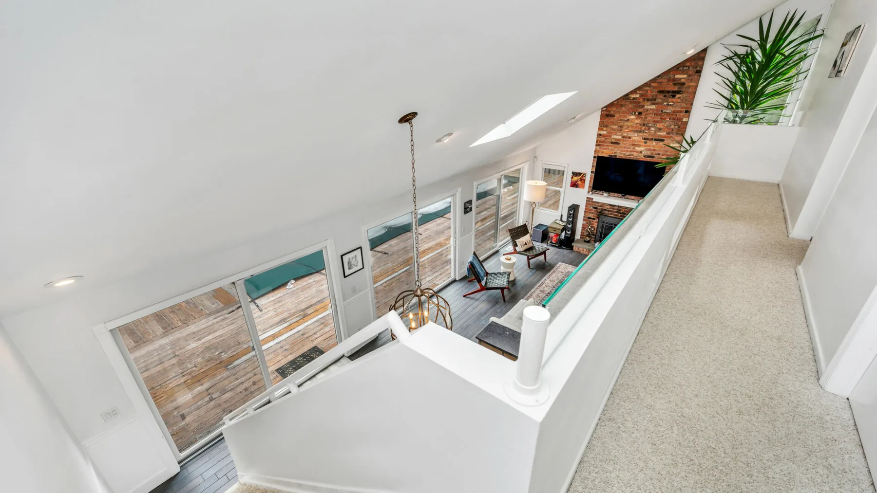 Una luminosa sala tipo loft con ventanales, asientos y una pared de ladrillo.