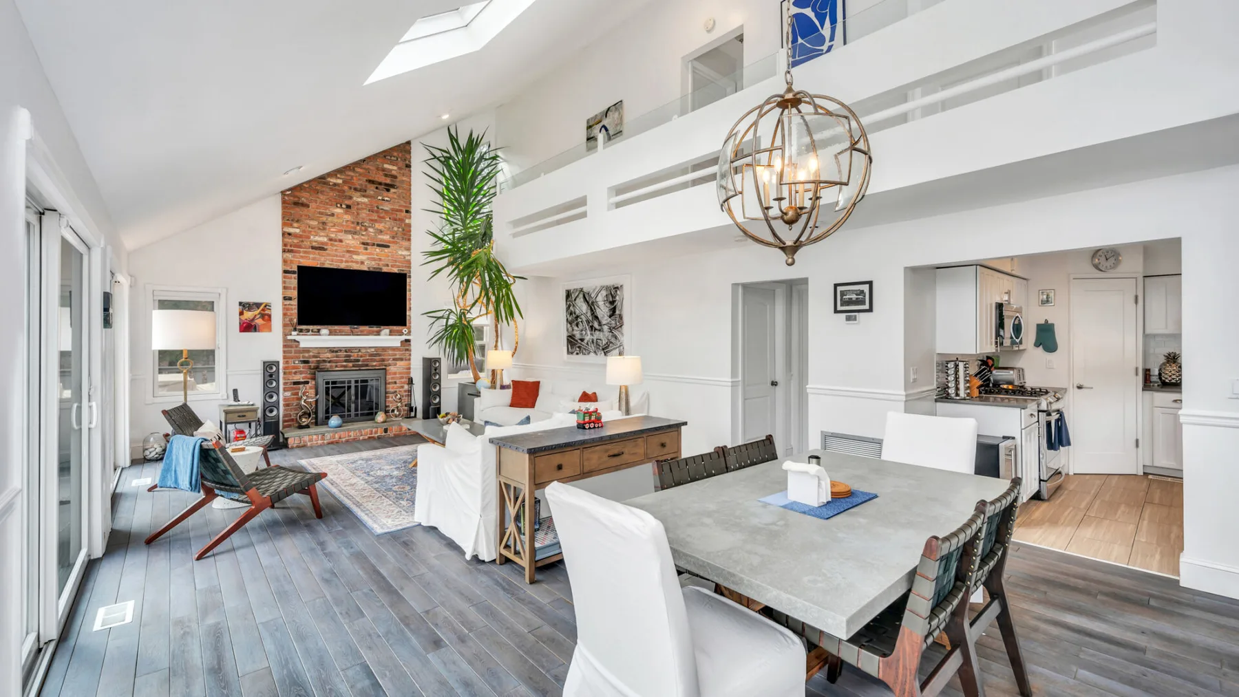 Una luminosa sala diáfana con comedor y chimenea de ladrillo.