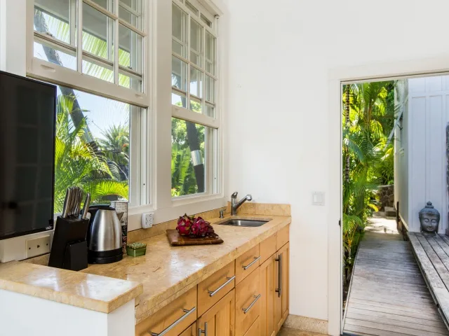 A bright kitchen with a countertop and large windows overlooking greenery.