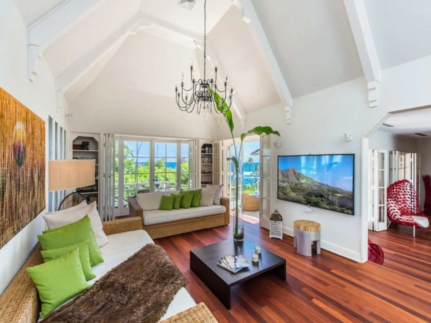 A bright living room with seating, large windows, and a television.
