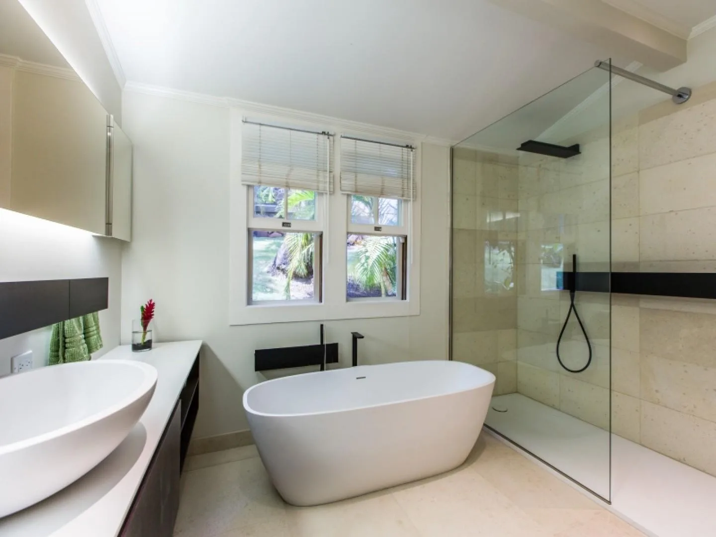 A bright bathroom with a freestanding bathtub and glass shower.