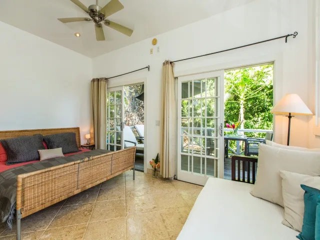 A bright living room with seating, sliding glass doors, and a ceiling fan.