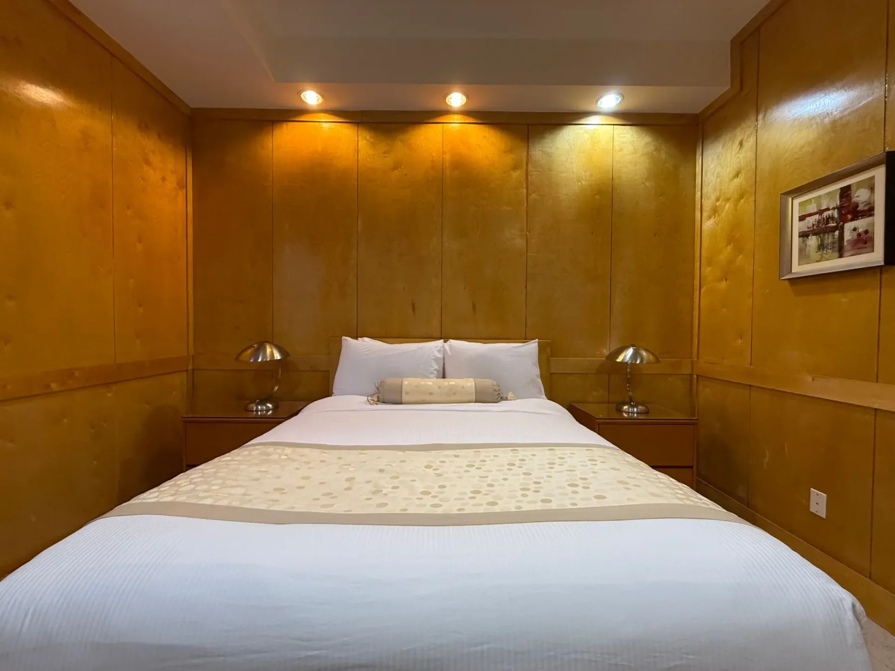 Dormitorio con cama y revestimiento de madera.