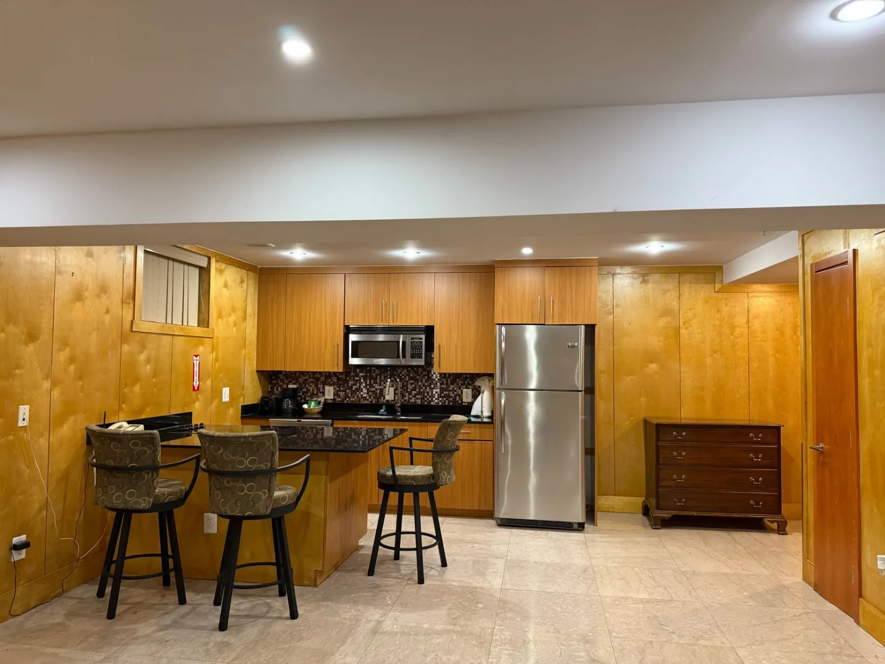 Cocina con refrigerador y taburetes de barra.