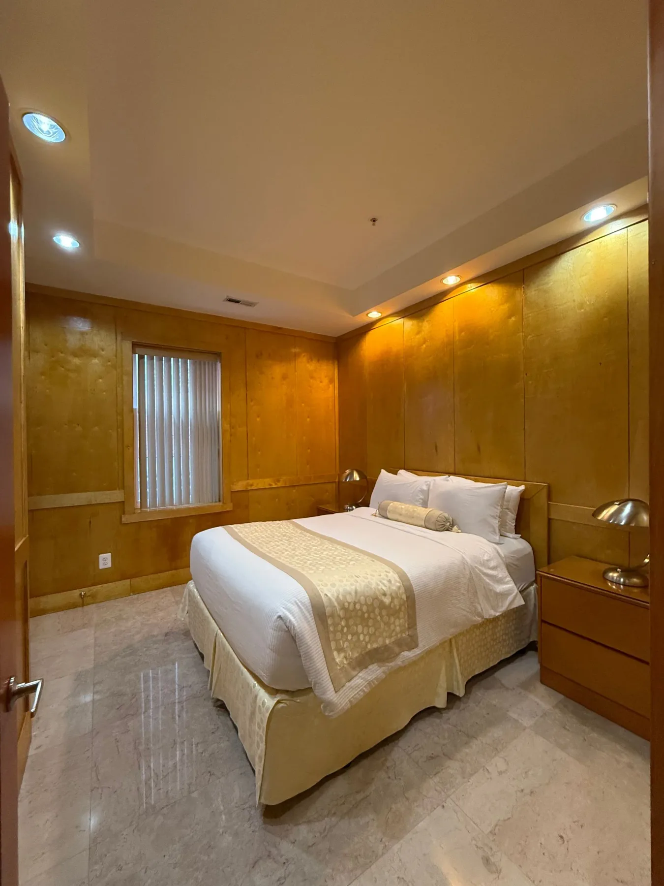 Dormitorio con cama y suelo de mármol.