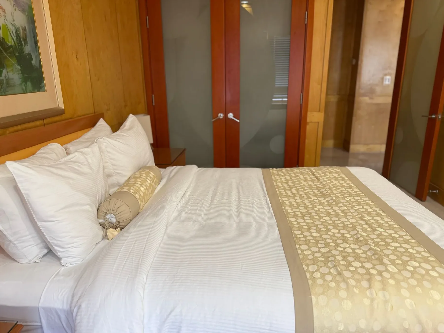 Cama con ropa de cama blanca en una habitación revestida de madera.