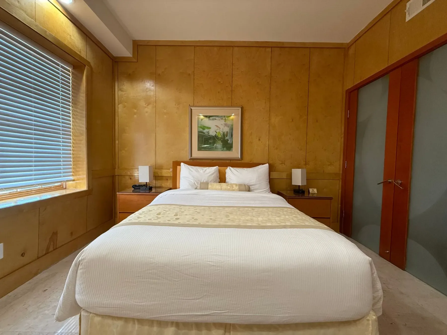 Dormitorio con cama y paredes revestidas de madera.