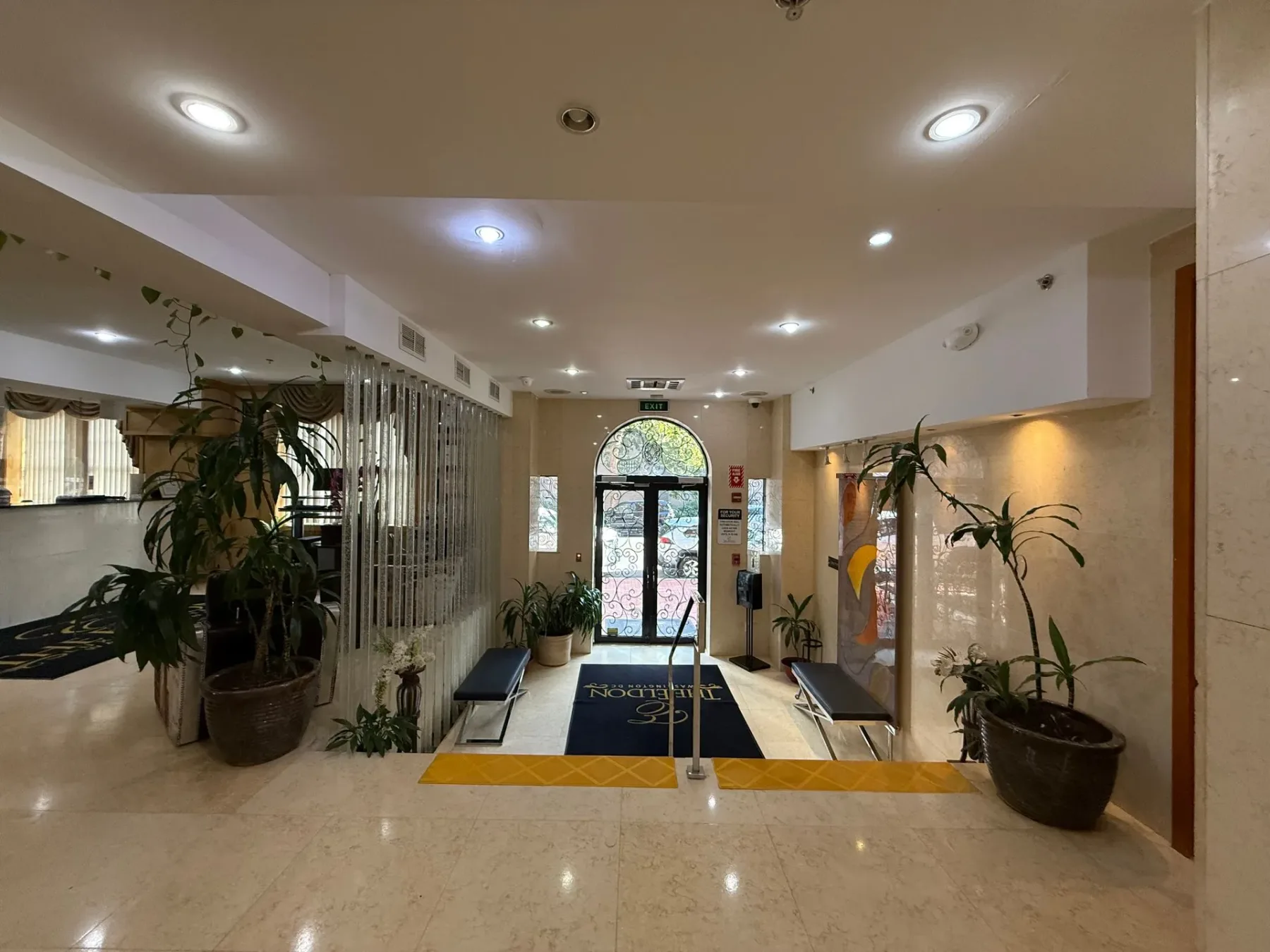Entrada al vestíbulo con bancos y plantas.