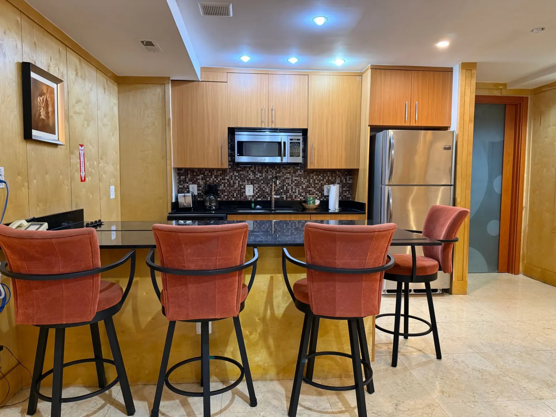 Cocina con asientos en la barra y refrigerador de acero inoxidable.
