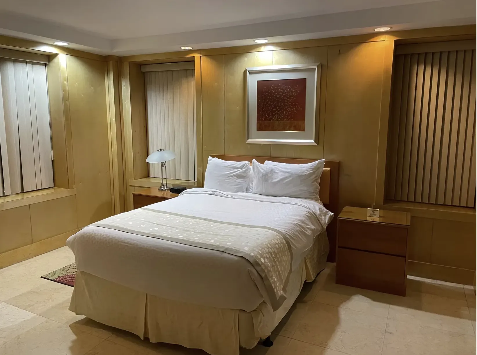 Dormitorio con cama, mesas de noche y ventanas.