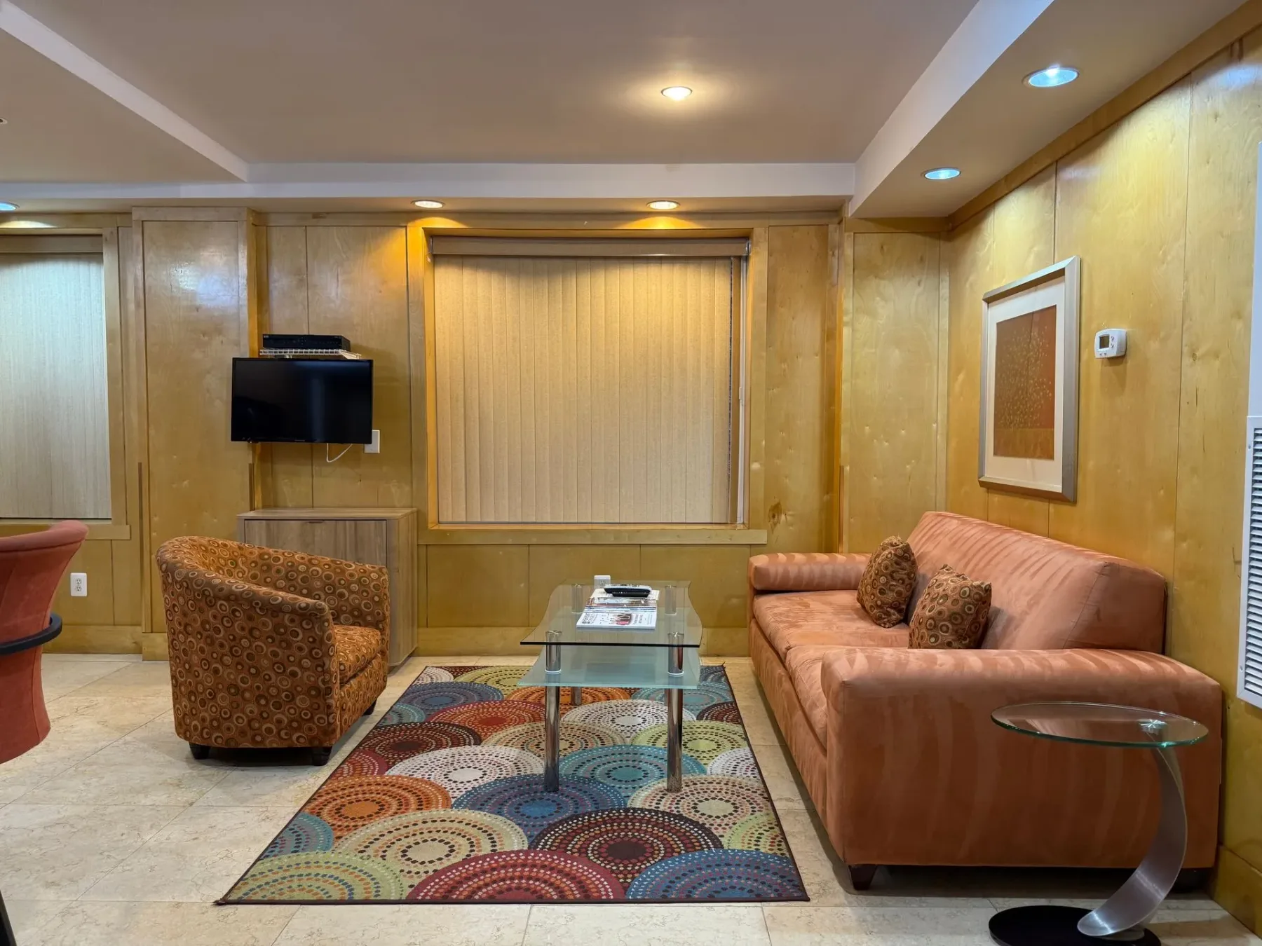 Sala de estar con sofá naranja y alfombra estampada.