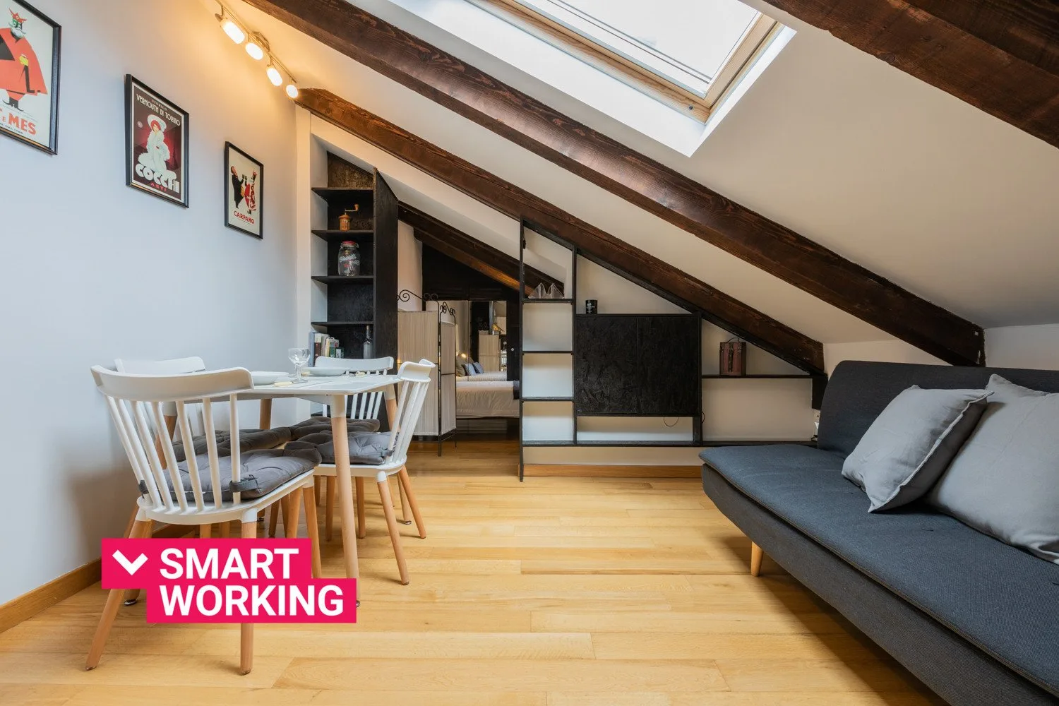 Attic living area with a sofa, dining table, and skylight.