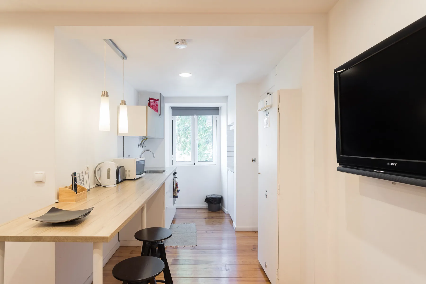 Una cocina compacta con zona de comedor, barra, taburetes y una ventana.