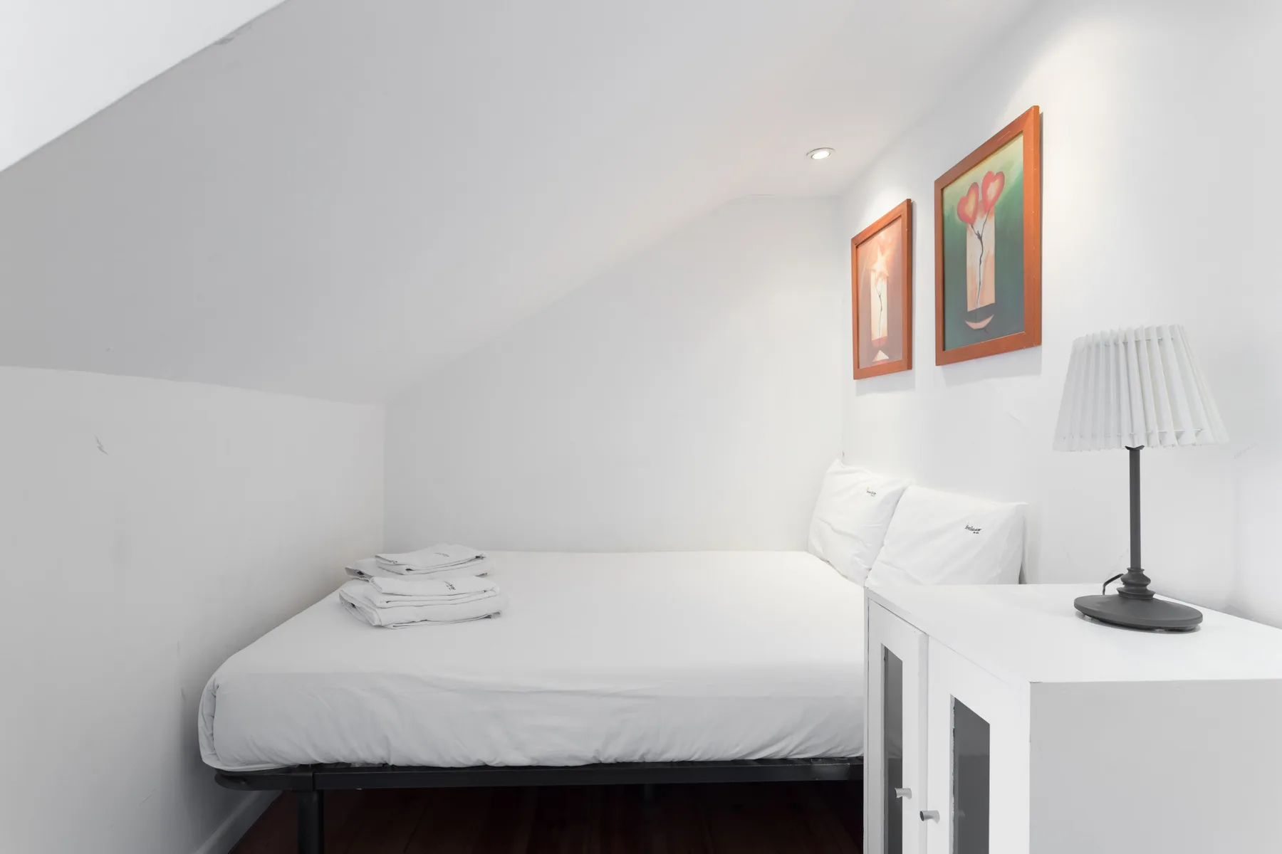 Un dormitorio con una cama bien hecha y una lámpara de noche.