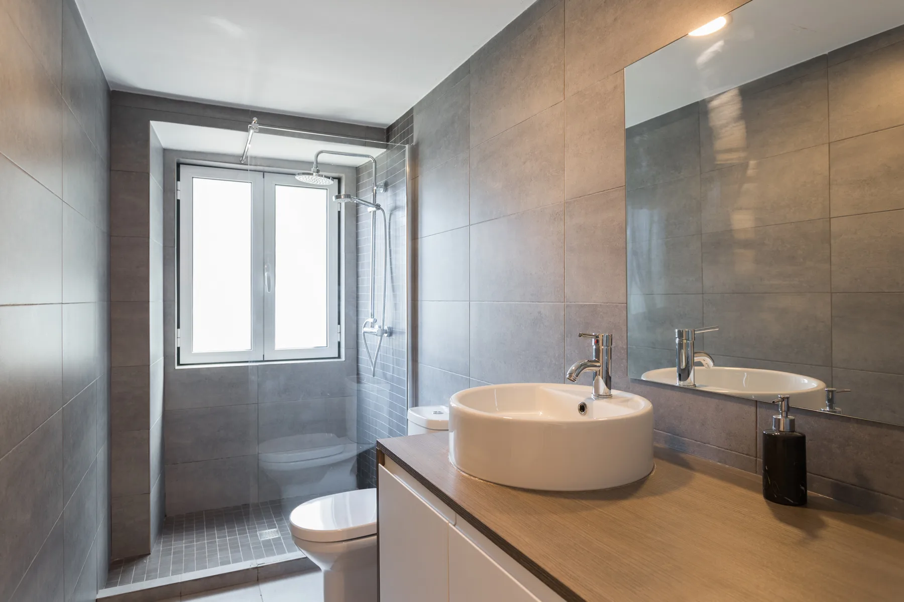 Un baño alicatado con lavabo, espejo y ducha.