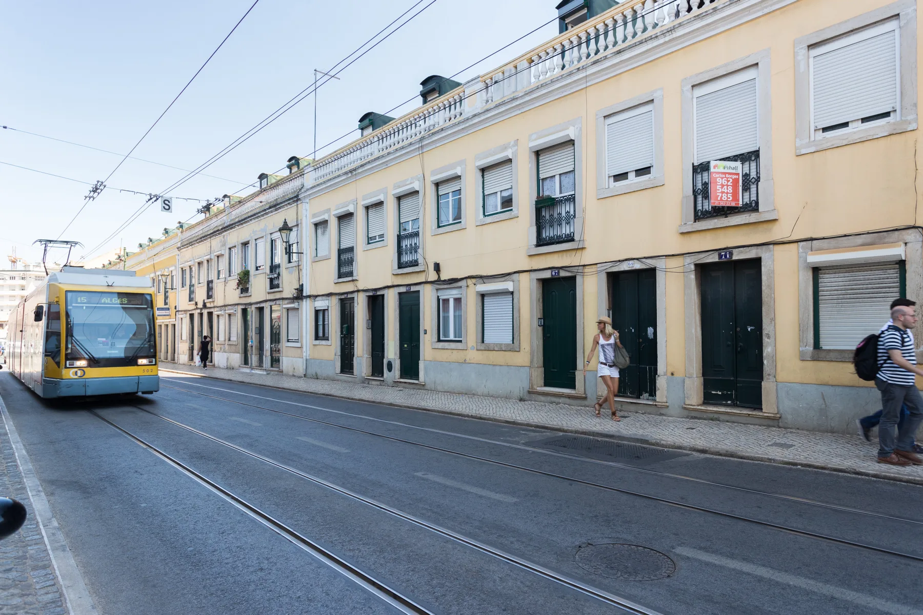 Un tranvía circula por una calle bordeada de edificios amarillos.