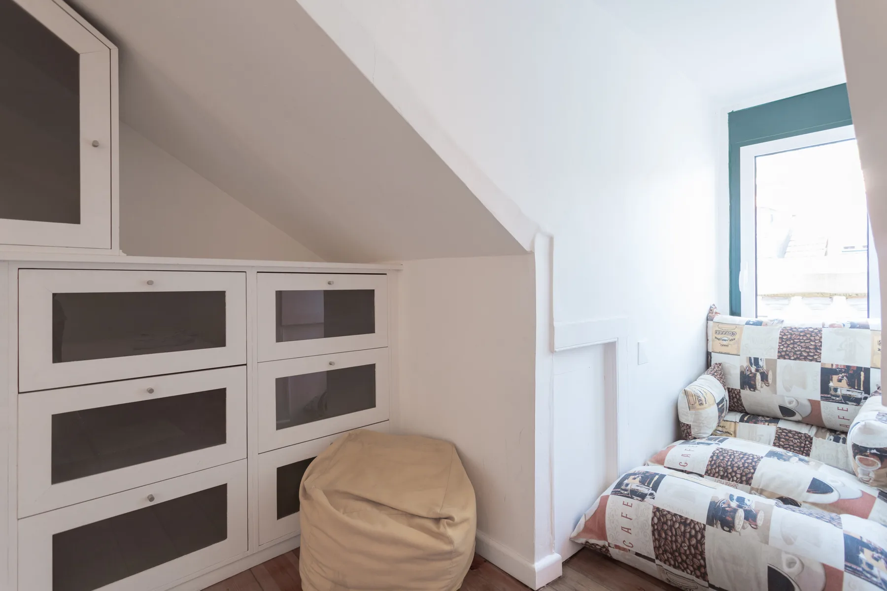 Un dormitorio compacto con armarios empotrados y una cama estampada junto a una ventana.