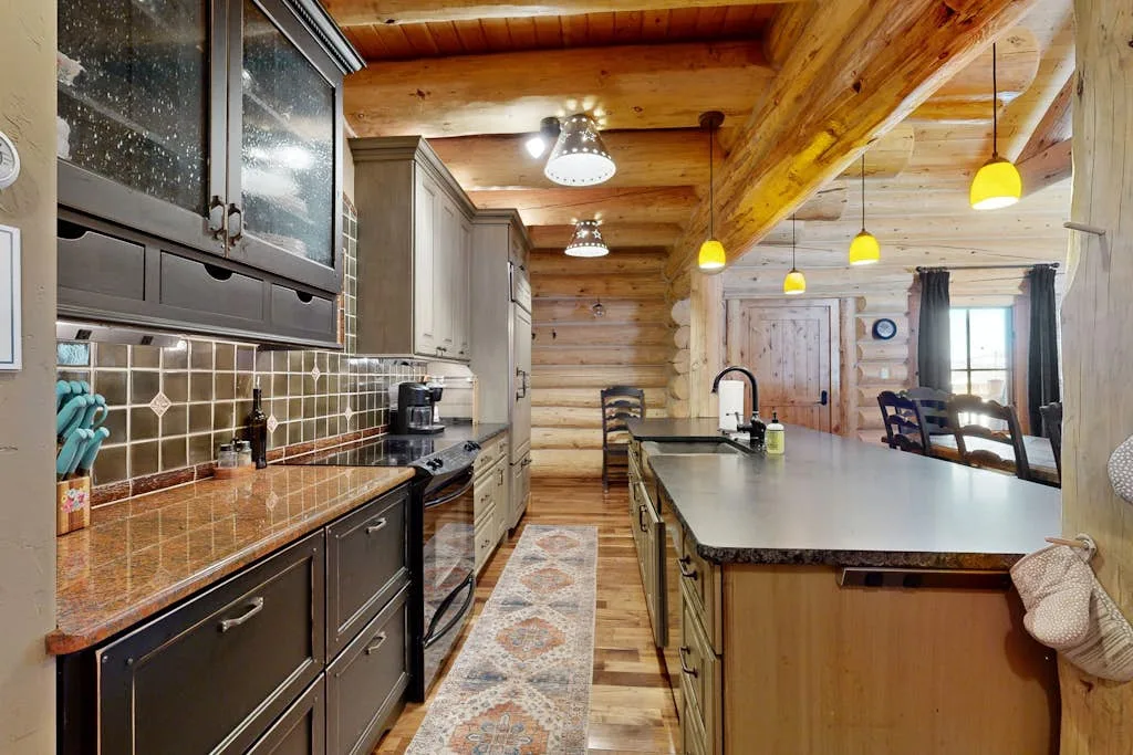 Una cocina revestida de madera con una isla central larga y lámparas colgantes.